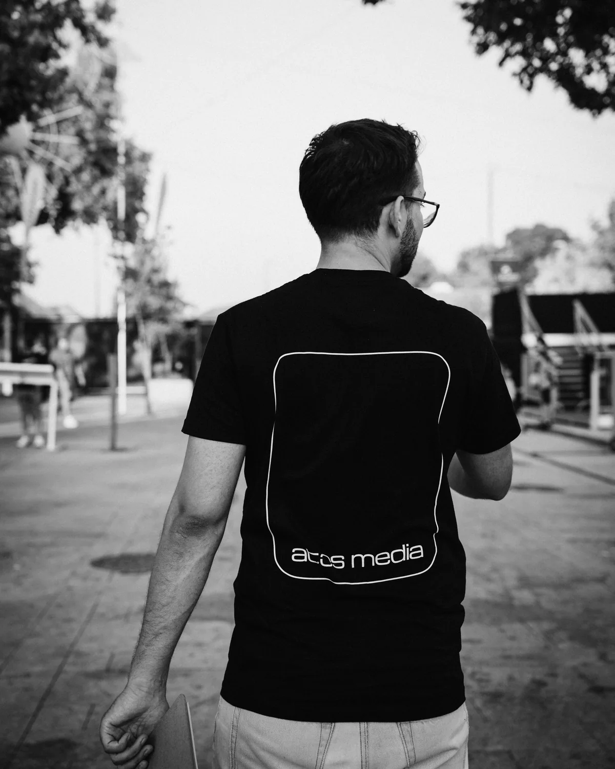 Elemento da equipa da Atos Media de costas, com a t-shirt da marca, durante um trabalho no exterior